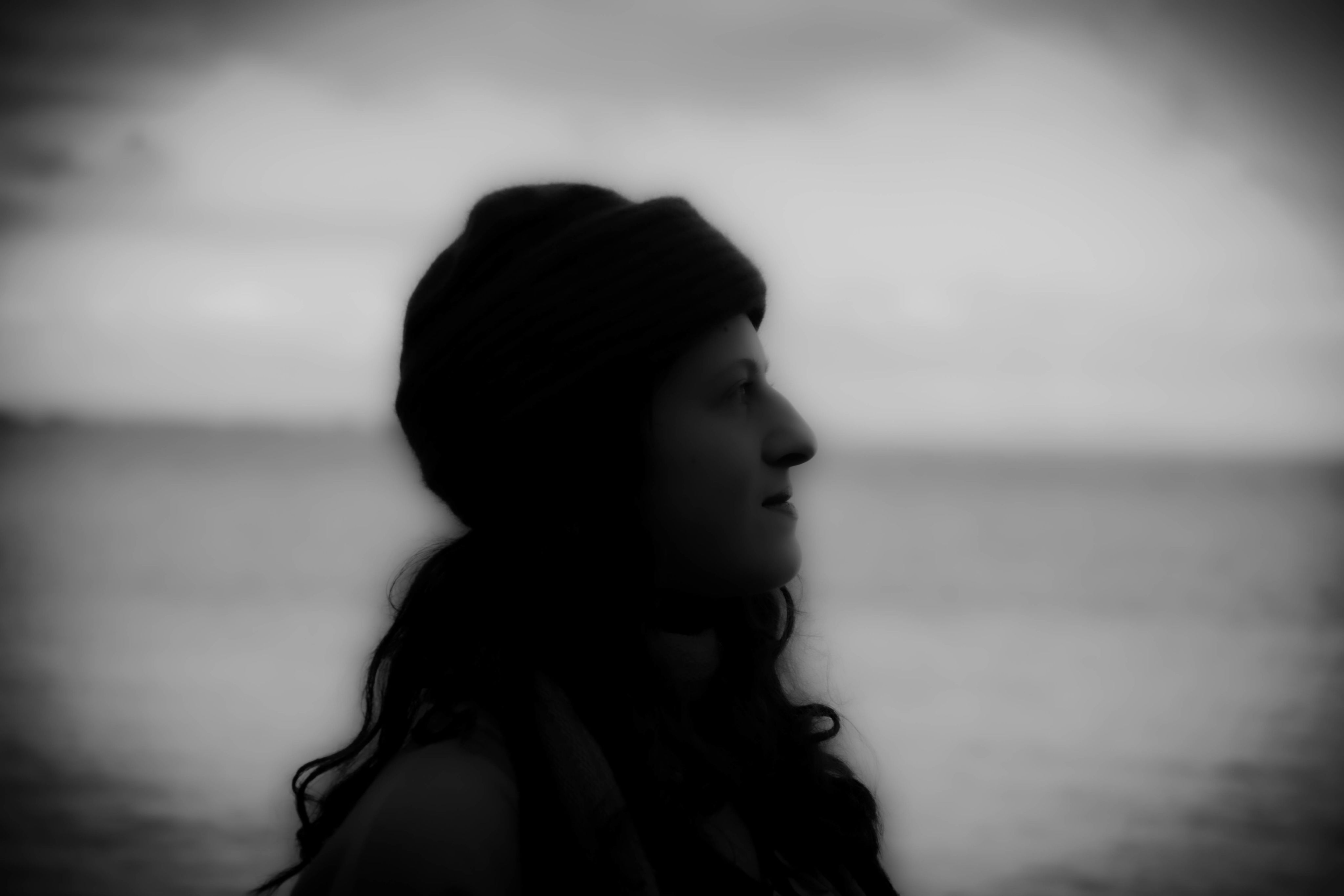 Black and white portrait of a woman near the ocean that is slightly out of focus.
