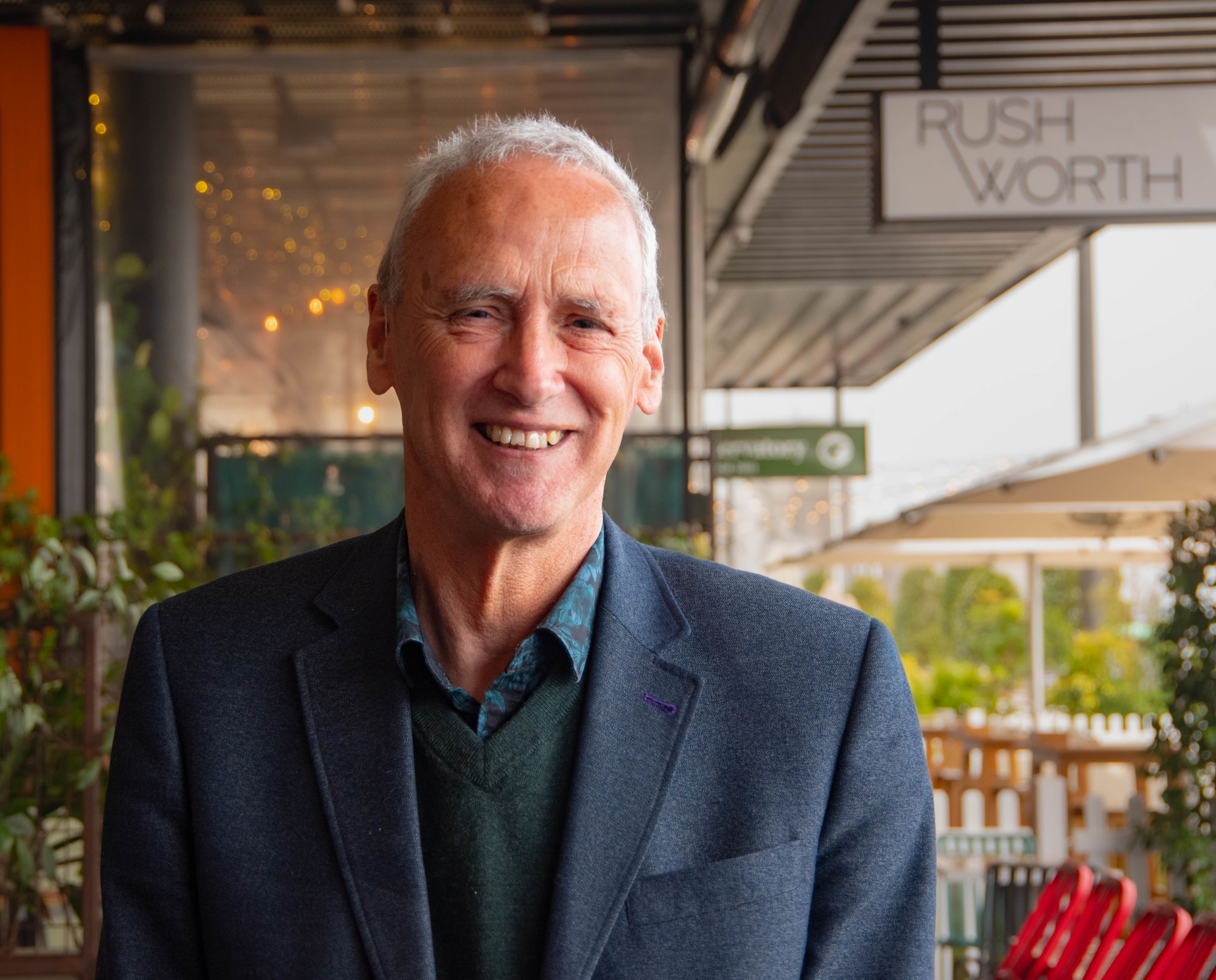 Colour photograph of Chris Higgins standing and smiling at the camera.