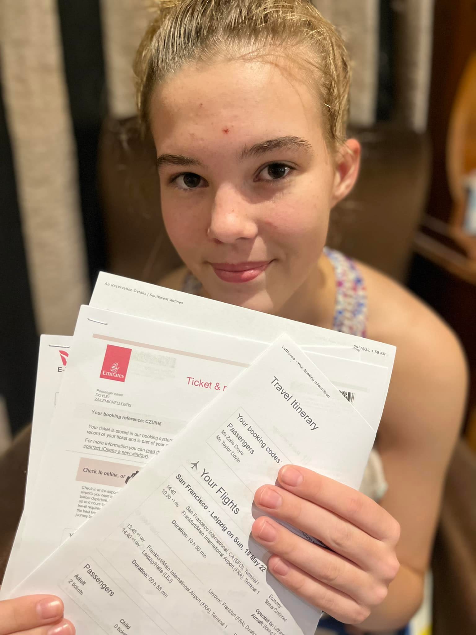 Photo of a teenage girl (Taylor) who is sitting and holding up travel itinerary documents.
